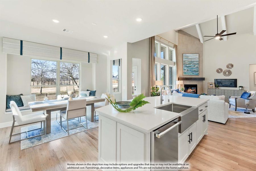 Open-concept kitchen with white island, flowing into dining area and living room with vaulted ceiling and fireplace Open-concept kitchen with white island, flowing into dining area and living room with vaulted ceiling and fireplace