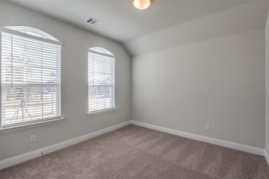 Room featuring two arched top windows with white horizontal blinds, light gray wall paint, light brown carpet flooring, and a flush mount ceiling light fixture