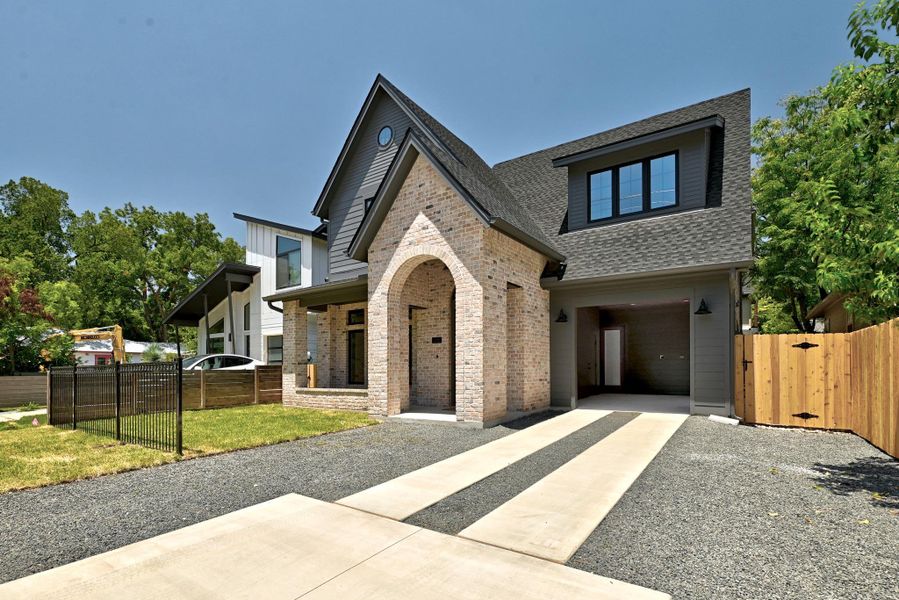 Modern facade showcases an arched brick entryway and integrated garage with striking dormer window. Modern facade showcases an arched brick entryway and integrated garage with striking dormer window.