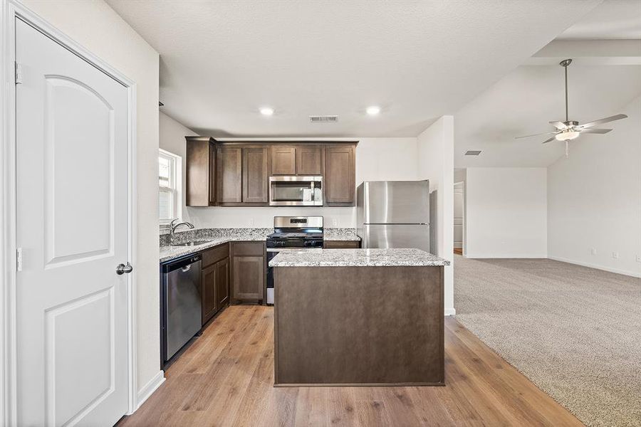 Kitchen featuring visible vents, a kitchen island, a sink, ceiling fan, and stainless steel appliances