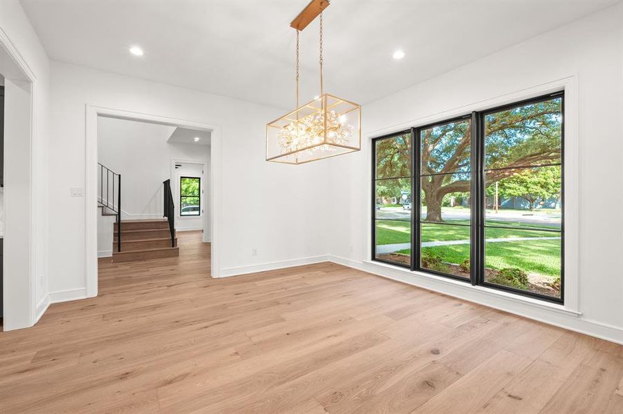 Unfurnished dining area with light wood-style flooring, a chandelier, recessed lighting, and stairs Unfurnished dining area with light wood-style flooring, a chandelier, recessed lighting, and stairs
