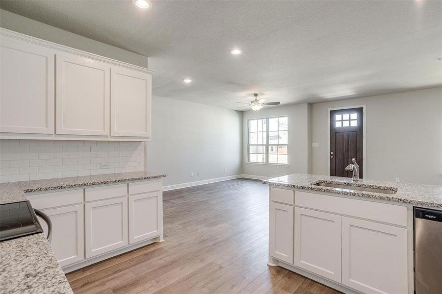 Kitchen featuring white cabinetry, light stone countertops, stainless steel dishwasher, a ceiling fan, and recessed lighting