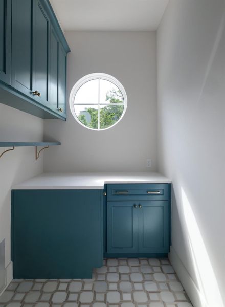 Laundry with side by side washer/dryer orientation and abundant cabinetry and shelving.