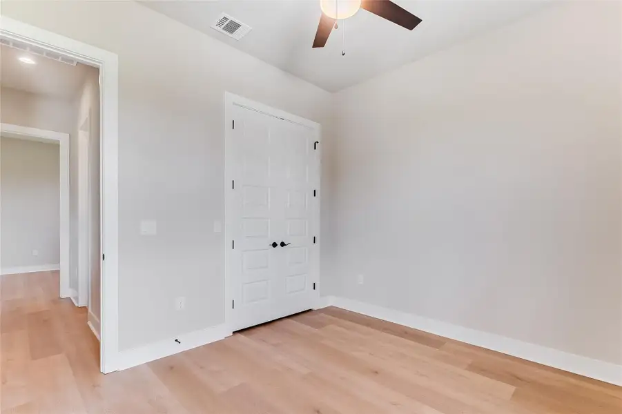 Unfurnished bedroom with light wood-type flooring, a ceiling fan, and a closet