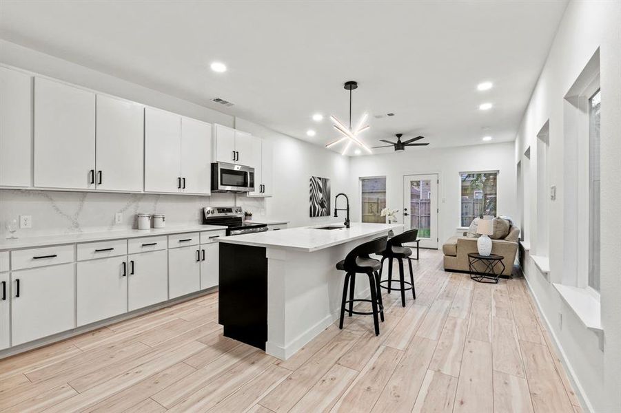 Kitchen with appliances with stainless steel finishes, a sink, light wood-type flooring, open floor plan, and recessed lighting Kitchen with appliances with stainless steel finishes, a sink, light wood-type flooring, open floor plan, and recessed lighting