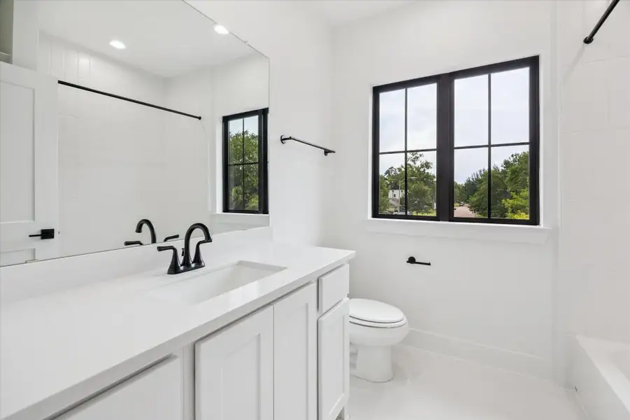 Crisp and bright, this secondary bathroom features clean white finishes, black matte fixtures, and natural light pouring in through a large window. Subtle contrast and simple detailing create a polished, timeless look. Crisp and bright, this secondary bathroom features clean white finishes, black matte fixtures, and natural light pouring in through a large window. Subtle contrast and simple detailing create a polished, timeless look.