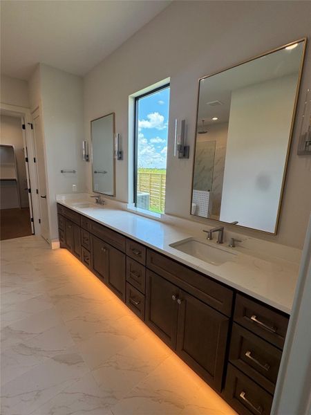 Spacious primary bath with dual vanities, custom cabinetry, and designer lighting.