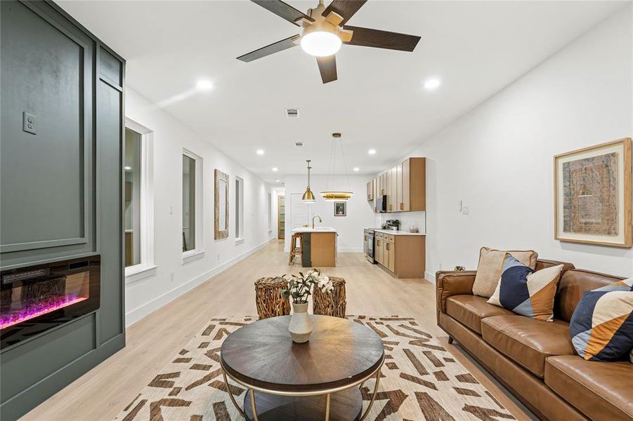 Living area featuring light wood finished floors, recessed lighting, a glass covered fireplace, and ceiling fan
