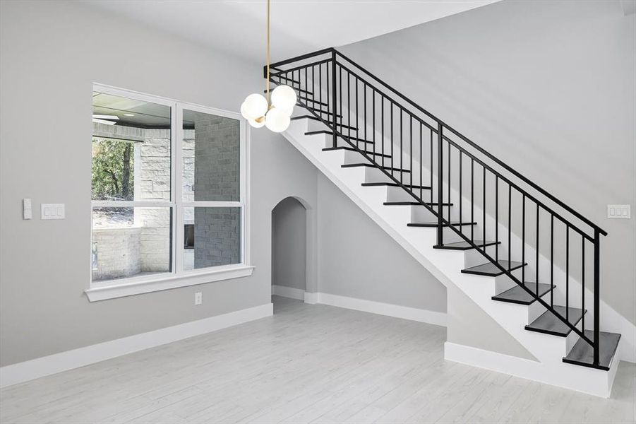 Stairs with wood finished floors, a chandelier, and arched walkways