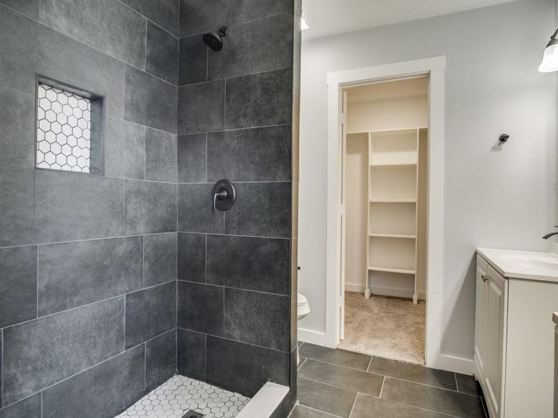 Bathroom featuring a tile shower, vanity, tile patterned flooring, and toilet Bathroom featuring a tile shower, vanity, tile patterned flooring, and toilet