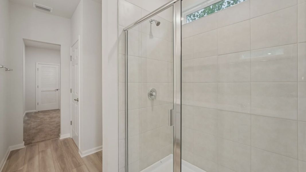 Luxurious glass shower and elegant tile walls highlight this Palm Coast owner's suite bathroom's refined design.