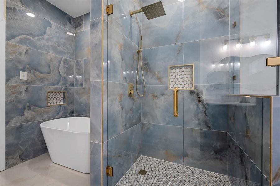 Spacious bathroom featuring a freestanding tub and a glass-enclosed shower with gold-tone fixtures Spacious bathroom featuring a freestanding tub and a glass-enclosed shower with gold-tone fixtures