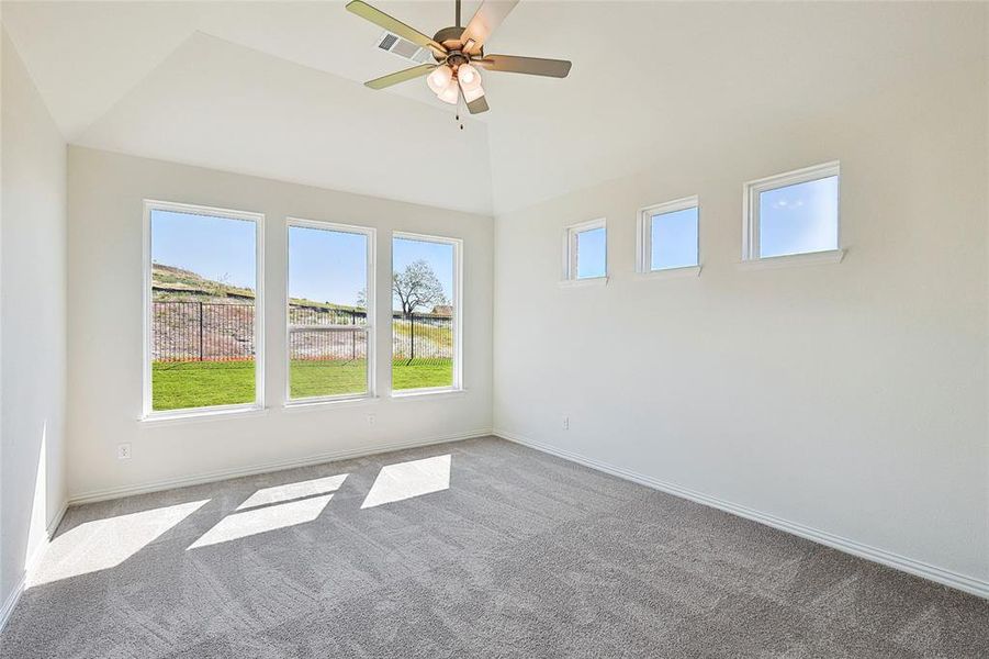 Carpeted spare room featuring ceiling fan and vaulted ceiling