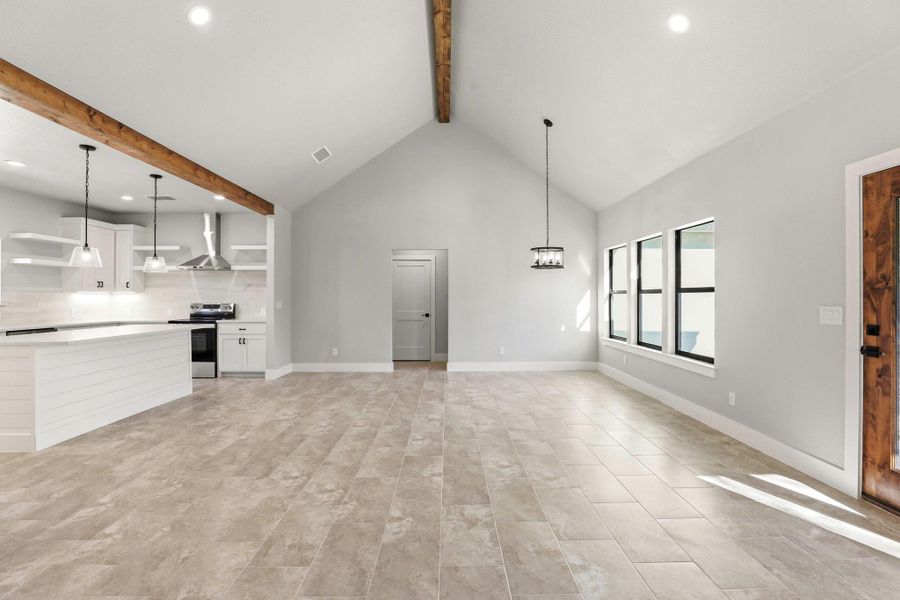 An open concept design seamlessly connects the kitchen and living area, highlighted by vaulted ceilings and a rich wood beam. An open concept design seamlessly connects the kitchen and living area, highlighted by vaulted ceilings and a rich wood beam.