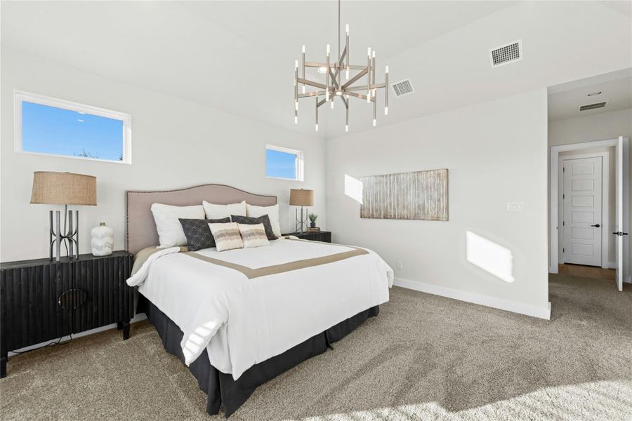 Bedroom featuring light carpet, multiple windows, and a chandelier Bedroom featuring light carpet, multiple windows, and a chandelier