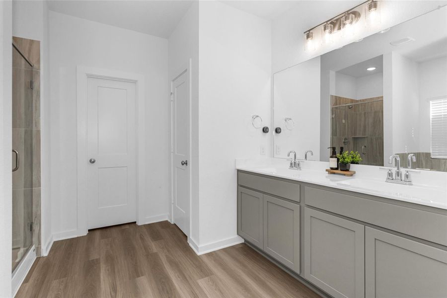 This spacious primary bathroom features a dual-sink vanity, large mirror, modern lighting, and a walk-in shower, creating a spa-like retreat.
