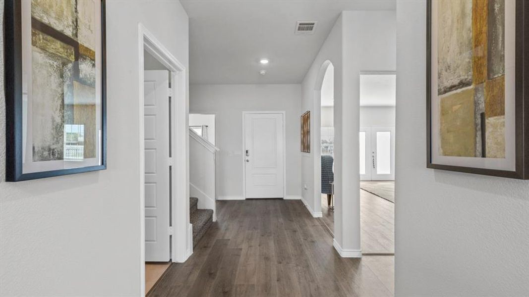 Inviting entry hall featuring wood-finish flooring, recessed lighting, arched doorways, and a prominent white front door Inviting entry hall featuring wood-finish flooring, recessed lighting, arched doorways, and a prominent white front door