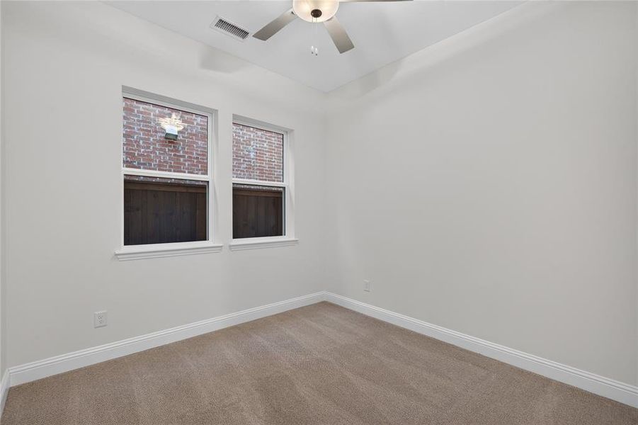 Neutral wall color with two white-framed windows, beige carpet flooring, white baseboards, and a ceiling fan with integrated lighting Neutral wall color with two white-framed windows, beige carpet flooring, white baseboards, and a ceiling fan with integrated lighting