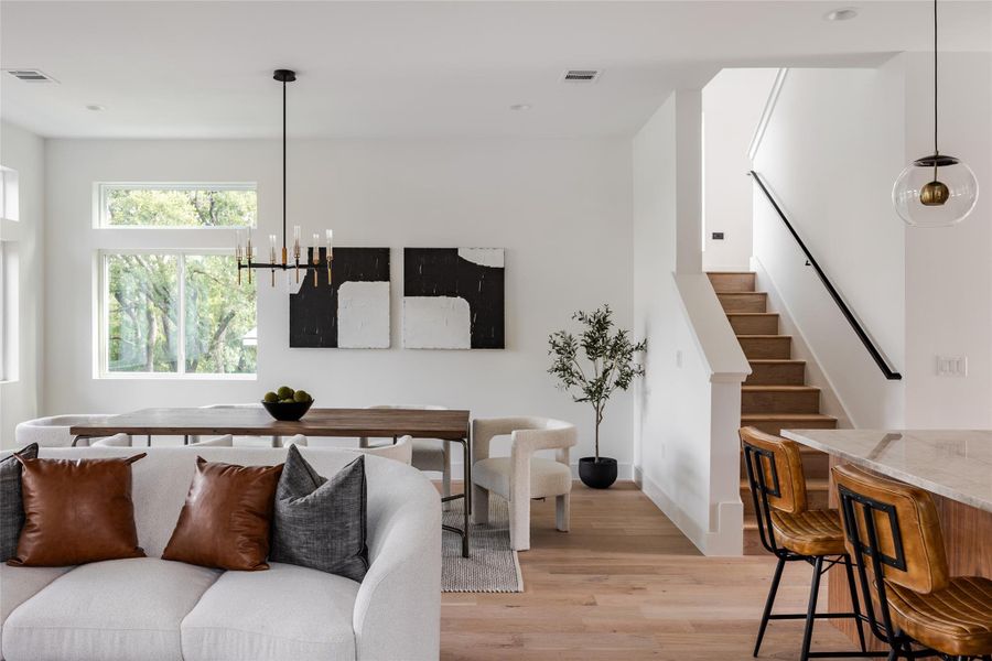 The spacious dining area effortlessly accommodates large gatherings, highlighted by a modern, minimalist chandelier that adds a touch of elegance to every meal.