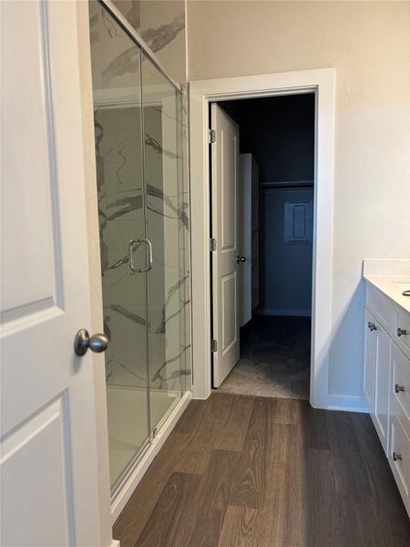 Bathroom with dark wood finished floors, vanity, and a marble finish shower
