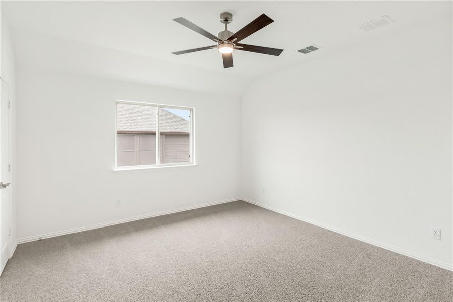Empty bedroom with vaulted ceiling, ceiling fan, carpet flooring, and single window Empty bedroom with vaulted ceiling, ceiling fan, carpet flooring, and single window