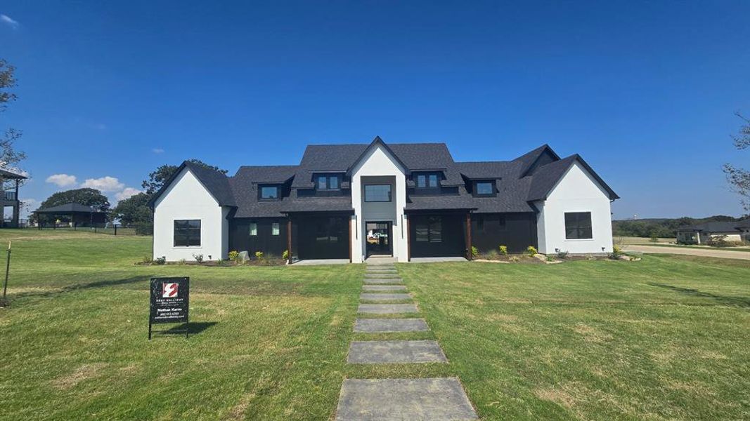 Modern farmhouse style home with a shingled roof, a front lawn, covered porch, and stucco siding