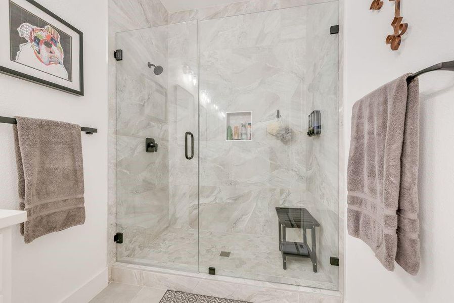 Full bath with a marble finish shower and baseboards