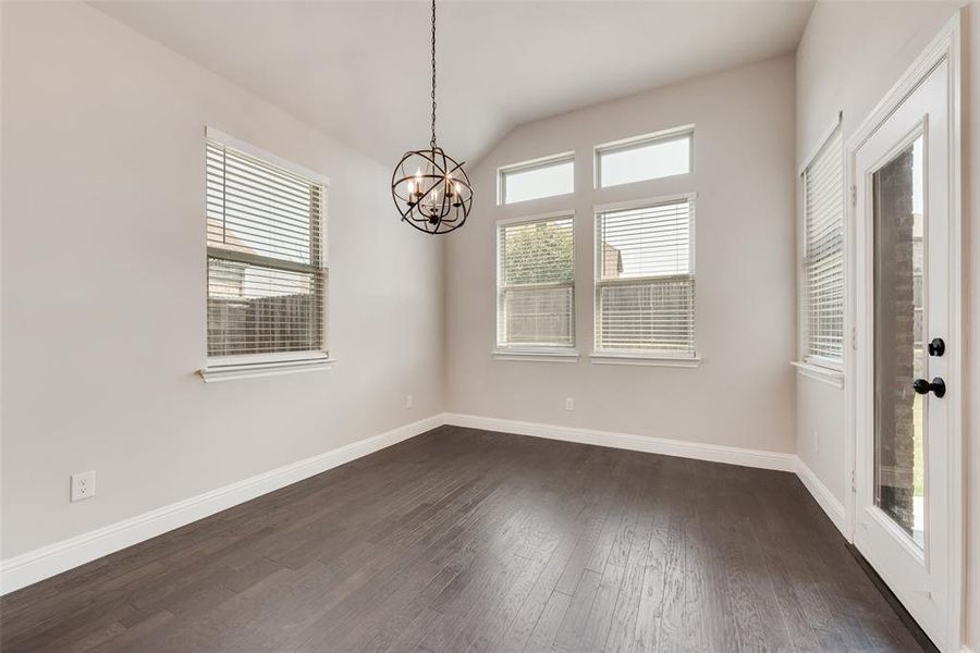 Spare room featuring dark wood-type flooring, vaulted ceiling, and a chandelier Spare room featuring dark wood-type flooring, vaulted ceiling, and a chandelier