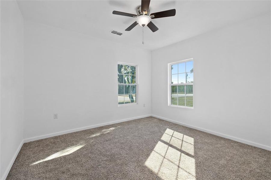 Empty room with carpet flooring and a ceiling fan Empty room with carpet flooring and a ceiling fan