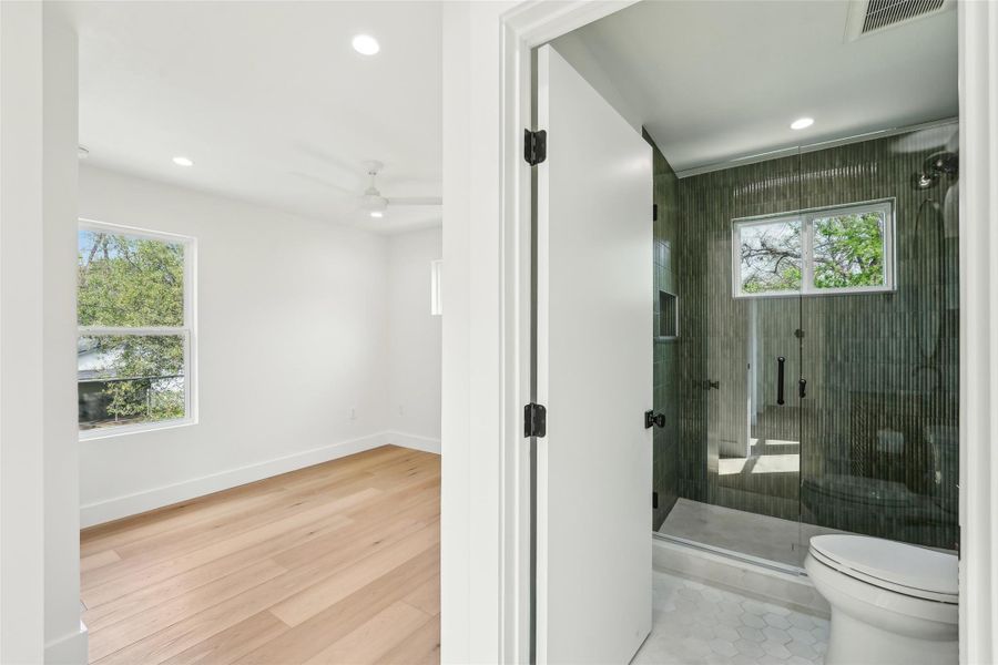 Full bath with recessed lighting, toilet, a stall shower, baseboards, and wood finished floors