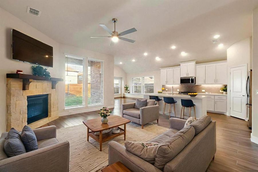 Living area featuring light wood-style floors, lofted ceiling, recessed lighting, a fireplace, and a ceiling fan