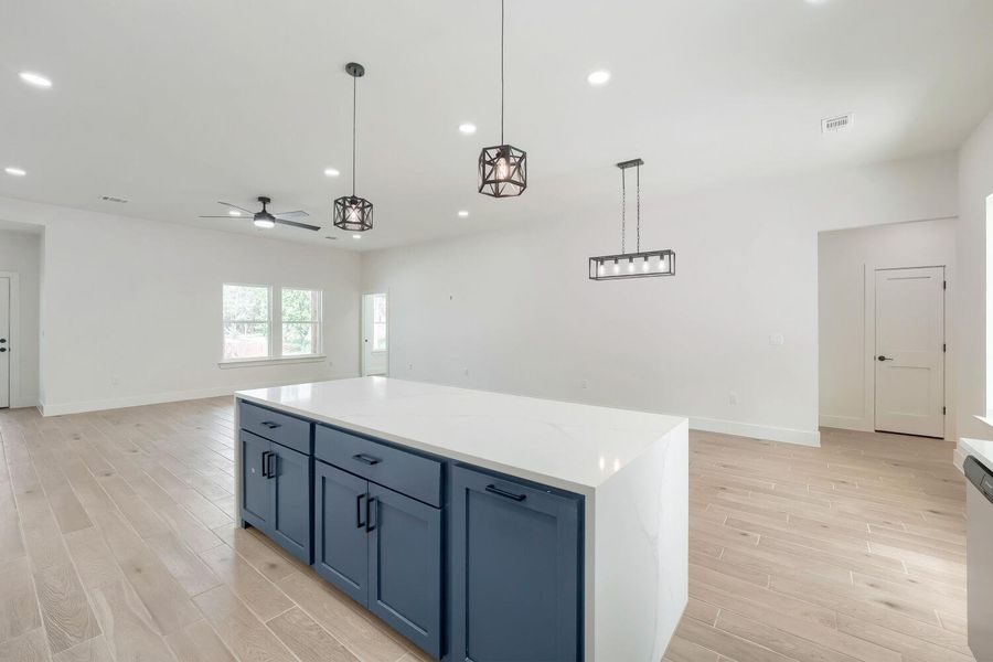 A spacious, open-concept interior showcasing a substantial kitchen island and light wood flooring.