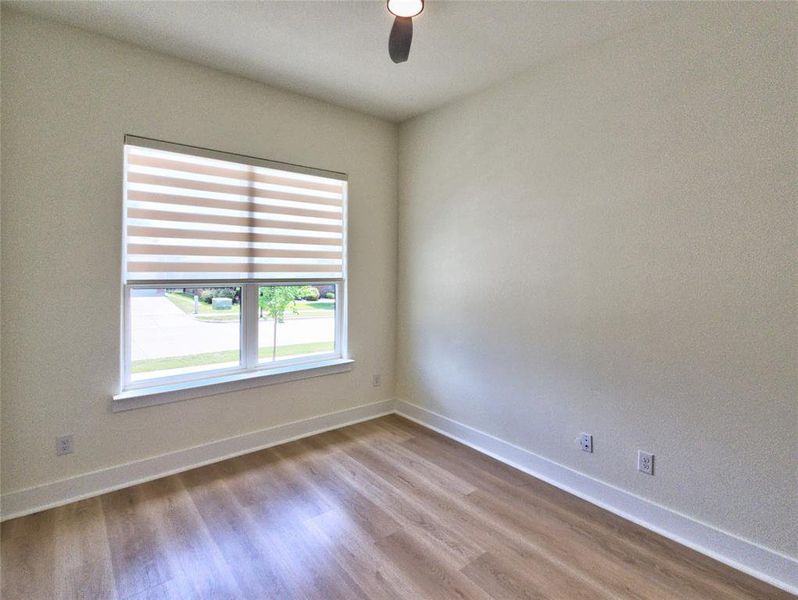 Room featuring wood-finish flooring, a double window with horizontal blinds, white baseboards, and neutral wall tones