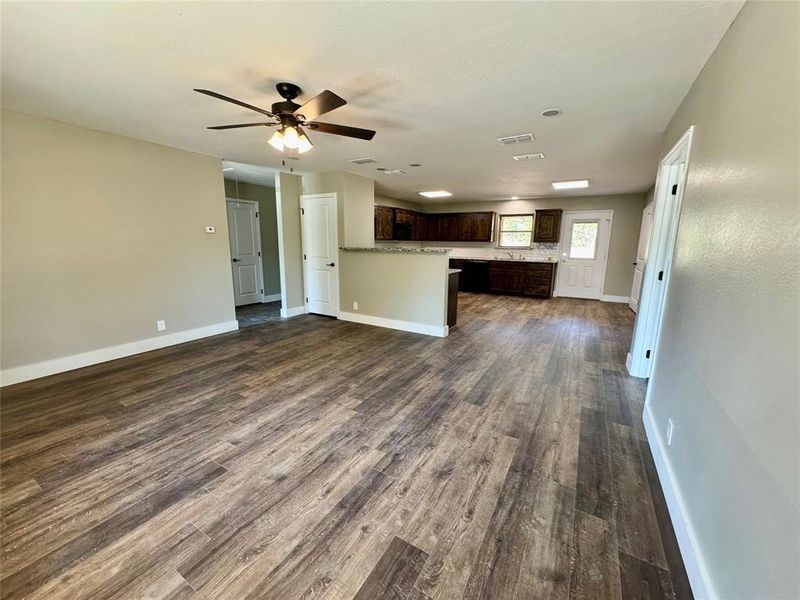 Unfurnished living room featuring dark wood finished floors and ceiling fan