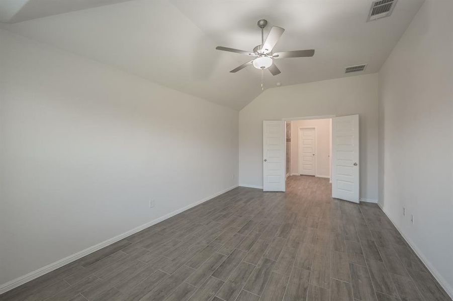 Unfurnished bedroom with lofted ceiling, a ceiling fan, and wood finish floors Unfurnished bedroom with lofted ceiling, a ceiling fan, and wood finish floors
