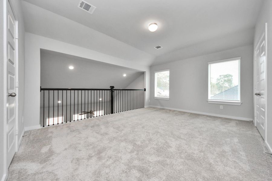 Discover a haven of leisure in this fantastic game room! Whether you're seeking a casual hangout or an adult gaming retreat, this space has it all. Enjoy the luxurious feel of plush carpet underfoot, the expansive ambiance of high ceilings, custom paint that adds a touch of personality, and windows that flood the room with refreshing natural light. Sample photo of completed home with similar floor plan. Actual colors and selections may vary.