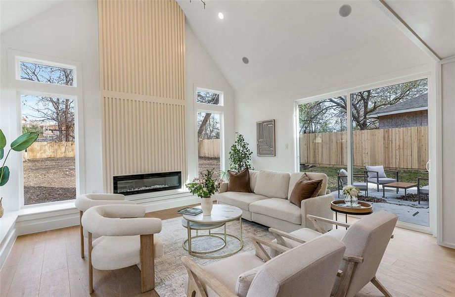 Living room featuring high vaulted ceiling, a large fireplace, and wood finished floors