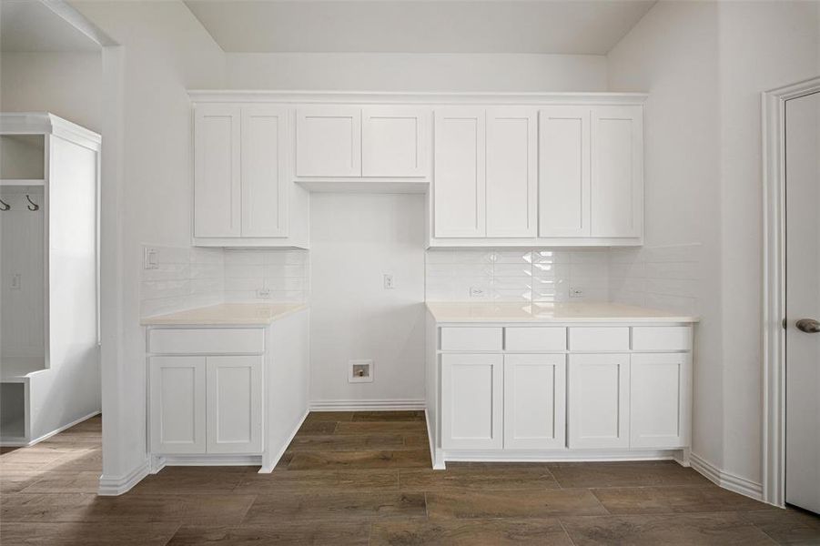 Kitchen with white cabinets, dark wood finished floors, tasteful backsplash, and light stone counters Kitchen with white cabinets, dark wood finished floors, tasteful backsplash, and light stone counters