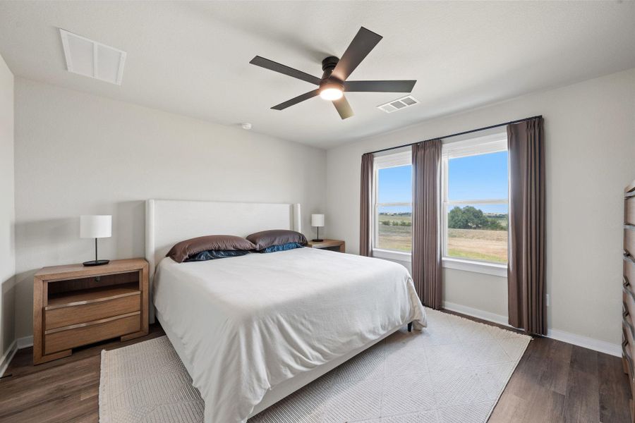 Double windows frame tranquil open views from this serene bedroom featuring rich wood flooring. Double windows frame tranquil open views from this serene bedroom featuring rich wood flooring.