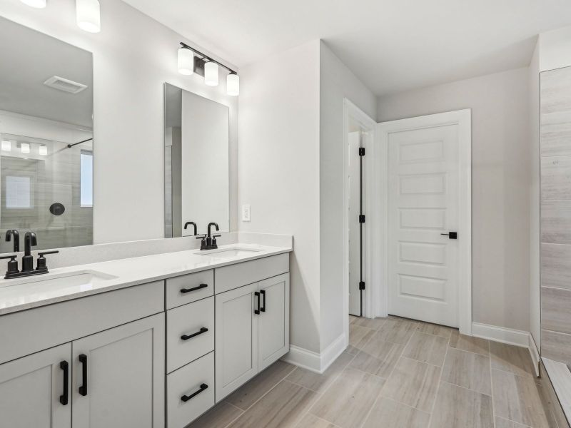 The primary bathroom features dual-vanity sinks and a walk-in shower.