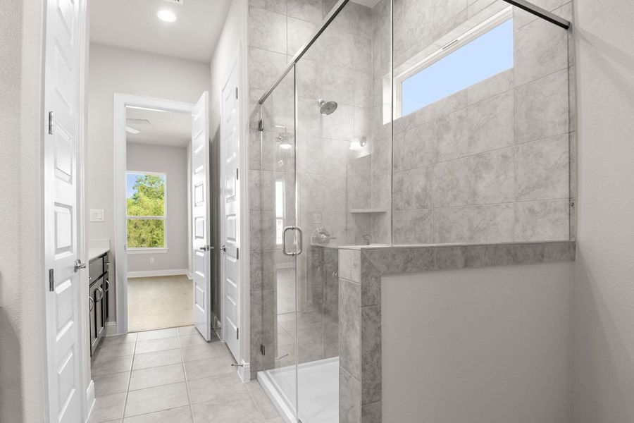 Image of primary bathroom with a walk in shower and white vanity and mirror