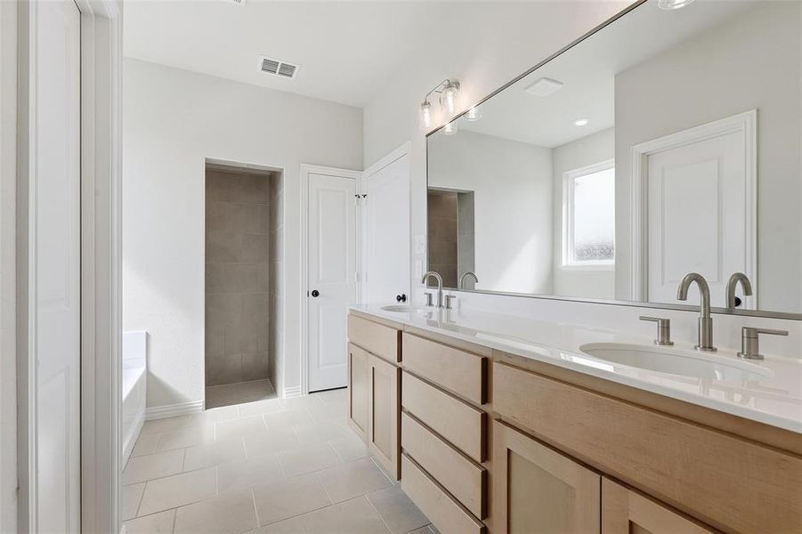 Bathroom featuring double vanity, a garden tub, and light tile patterned flooring Bathroom featuring double vanity, a garden tub, and light tile patterned flooring