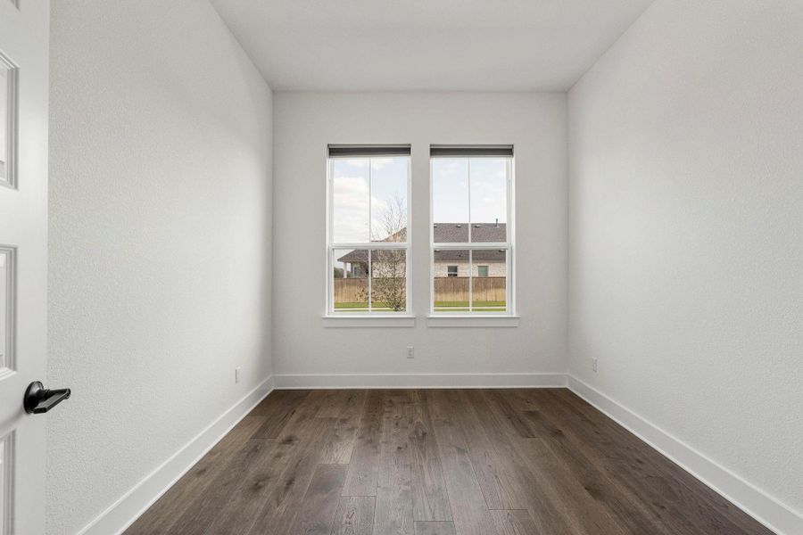 A versatile room features rich wood flooring, offering a flexible space for any lifestyle.