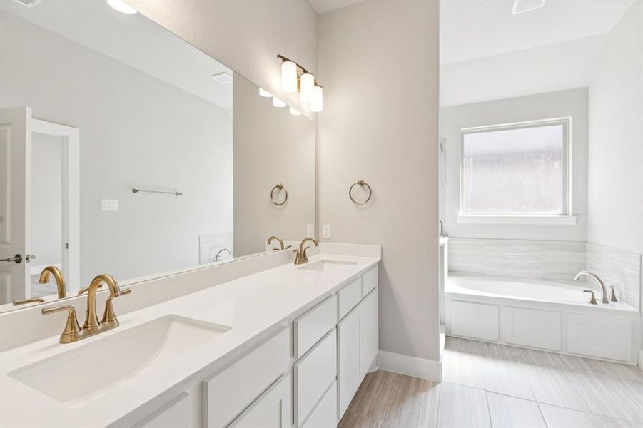 Full bath featuring a bath and double vanity