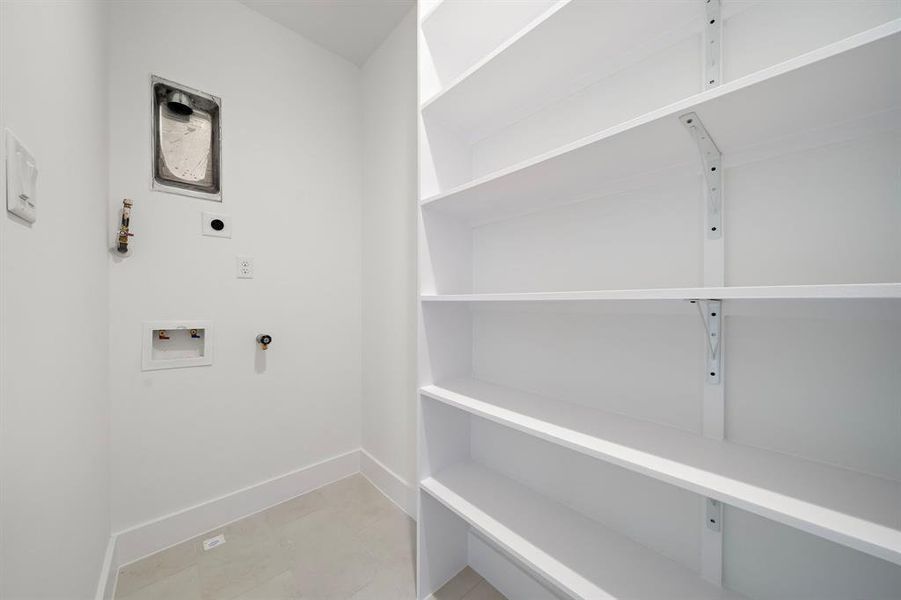 This laundry room features plenty of shelving to keep everything organized.