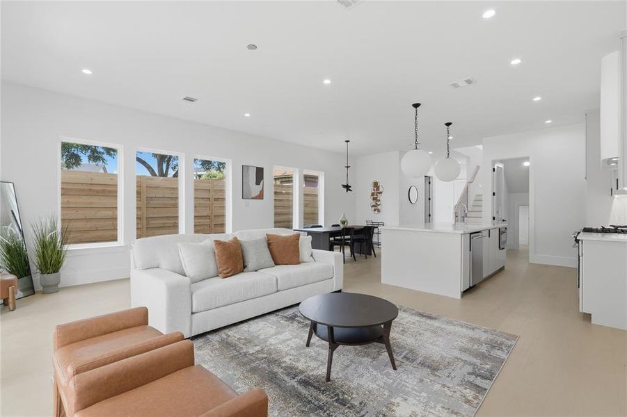 Open concept living area featuring light-toned flooring, recessed lighting, and a kitchen island with pendant lighting