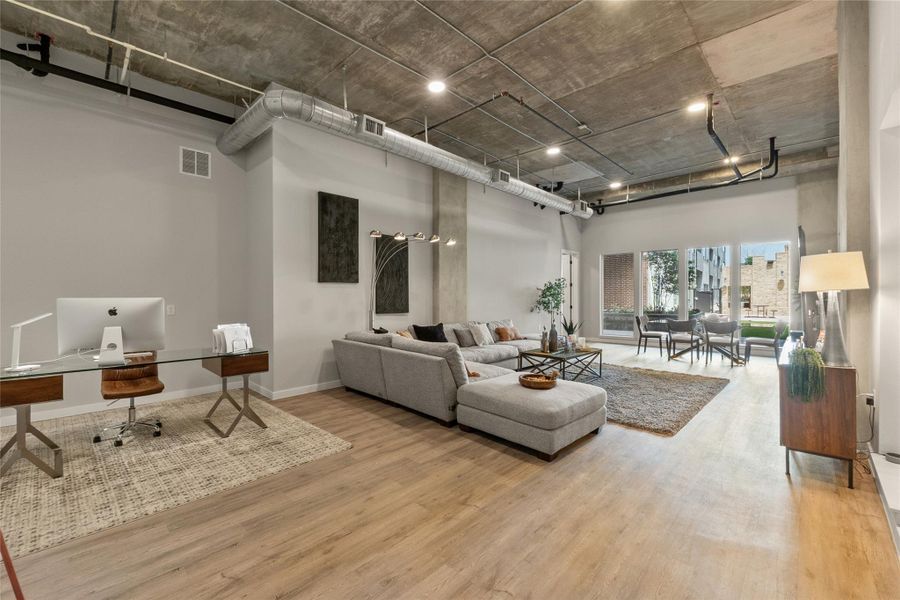 Living room featuring a high ceiling, wood finished floors, and an office area