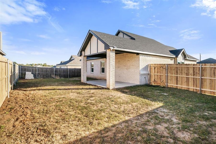 Back of house featuring a patio, brick siding, a fenced backyard, and a shingled roof