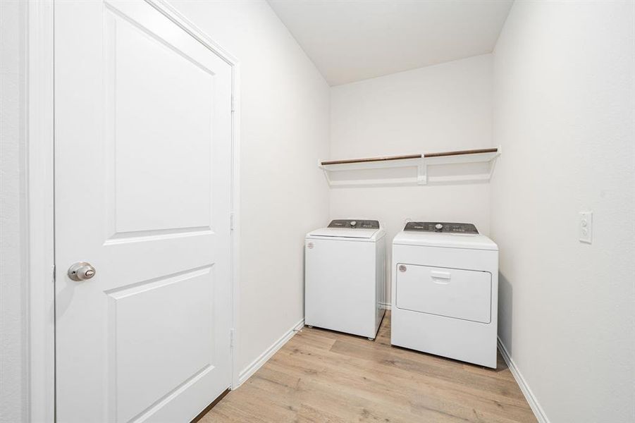 Laundry area with light wood-type flooring and washer and clothes dryer Laundry area with light wood-type flooring and washer and clothes dryer