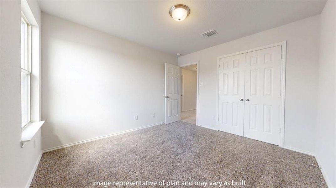 Carpeted room featuring a double-pane window, flush mount ceiling light fixture, white interior walls, and a bi-fold closet with panel doors Carpeted room featuring a double-pane window, flush mount ceiling light fixture, white interior walls, and a bi-fold closet with panel doors